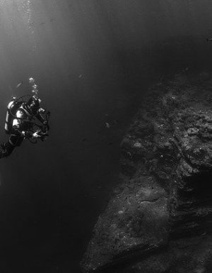 photo noir et blanc d'un plongeur au dessus d'une épave