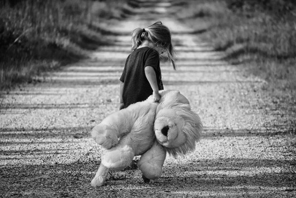 photo noir et blanc d'une enfant traînant une peluche