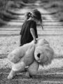 photo noir et blanc d'une enfant traînant une peluche